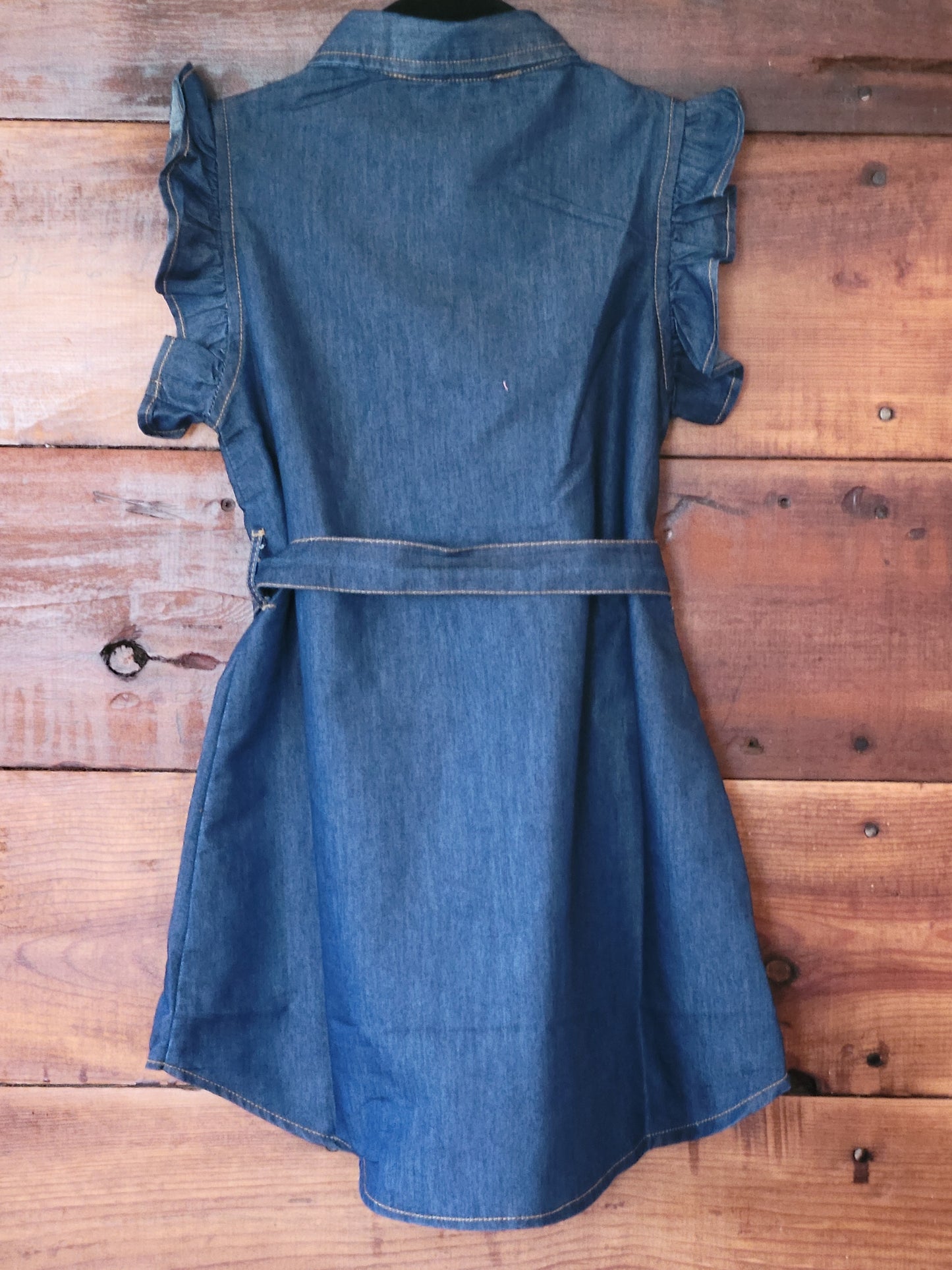 Blue denim dress with ruffled sleeves on a wooden background