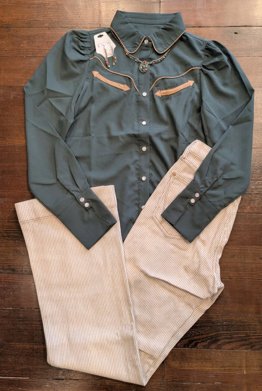 Forest green long-sleeve pearl snap shirt with gathered shoulders and contrast trim, paired with tan pinstripe pants, earrings, and a pendant necklace.