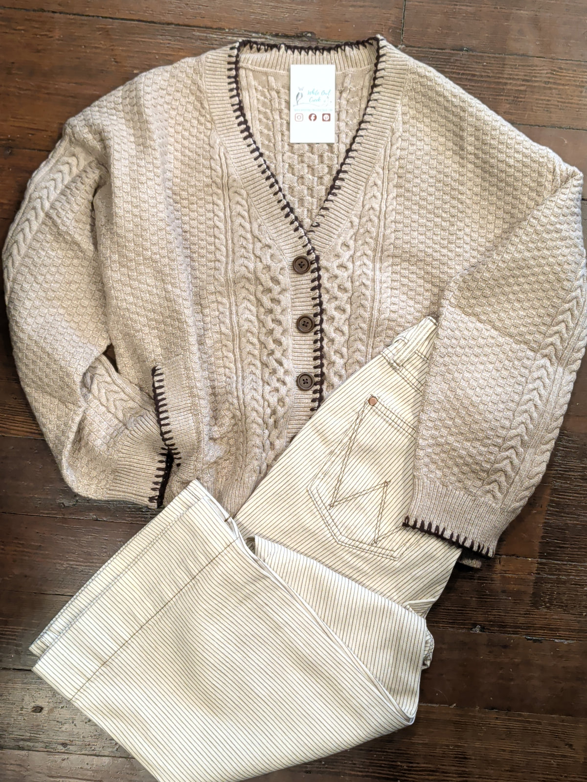 Mocha Blanket Stitch Cardigan styled with cream pinstriped pants in a flat lay on a wooden floor.