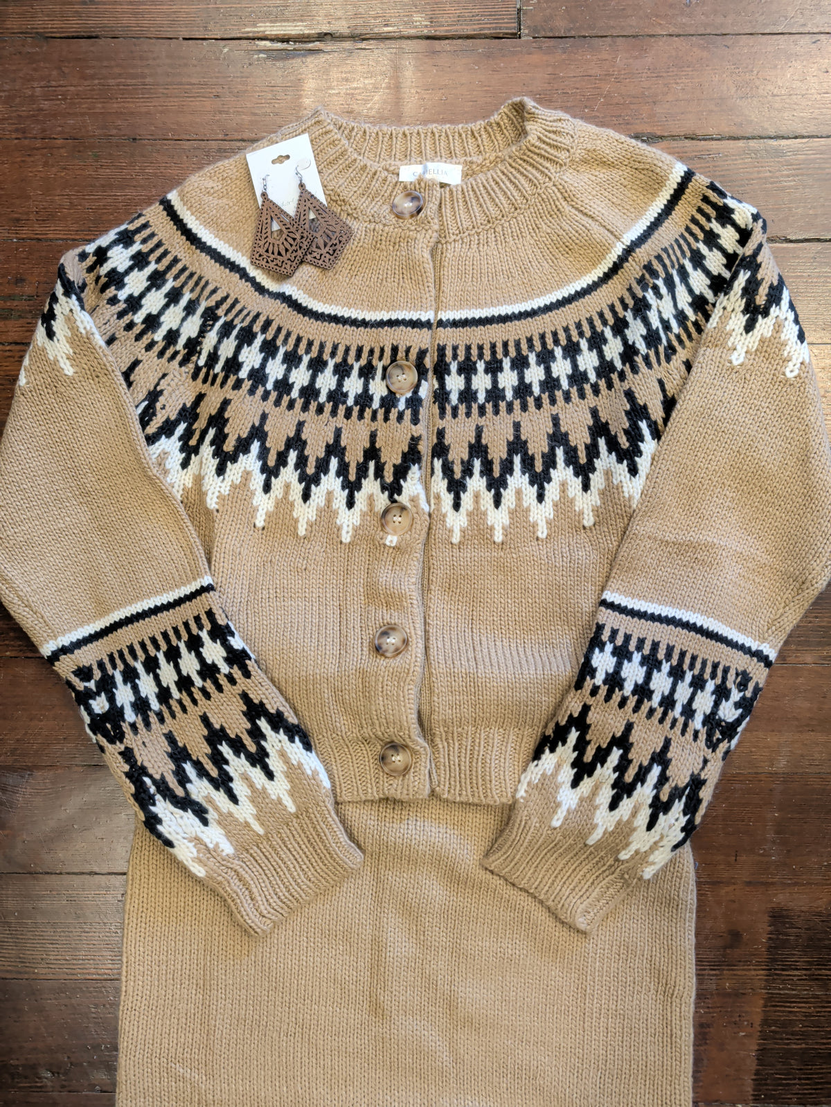 Close-up of light brown Fair Isle cardigan showing buttons and patterned knit, styled with a matching skirt and earrings.