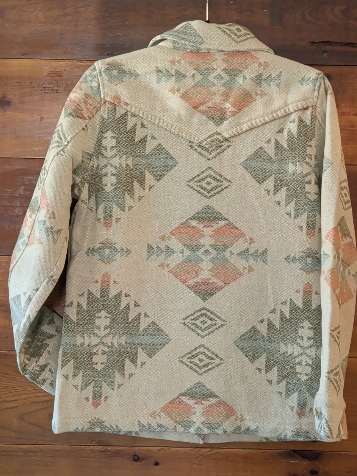 Back view of the cream Southwestern print coat with a pointed Western yoke and blanket stitch accents