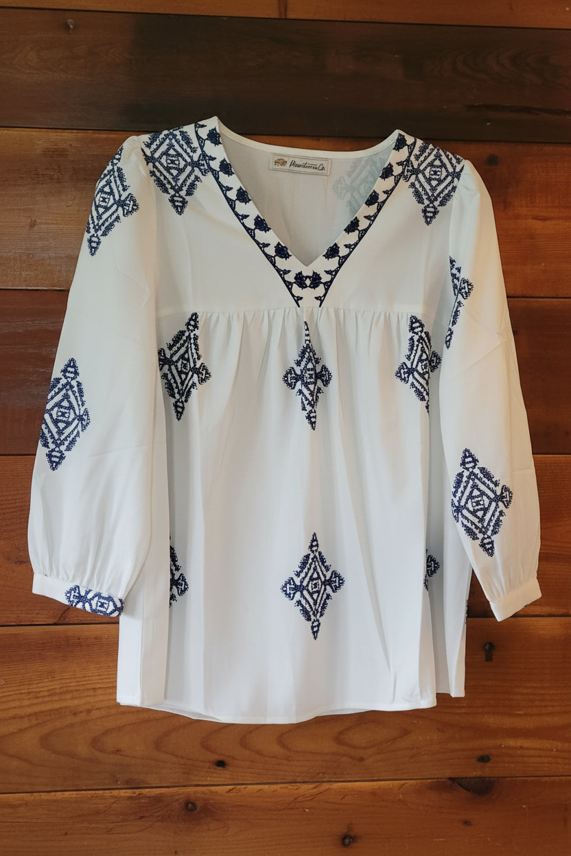 White blouse with blue geometric patterns on a wooden surface