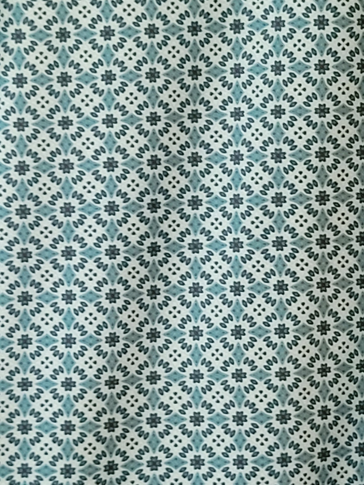 Patterned fabric with a geometric design in teal, black, and white.