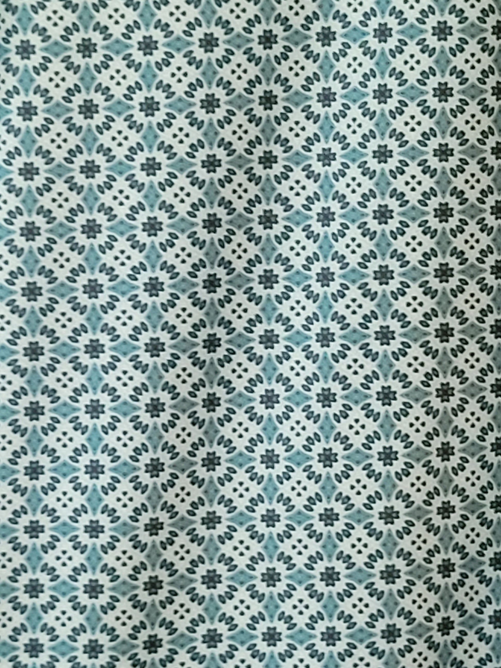 Patterned fabric with a geometric design in teal, black, and white.