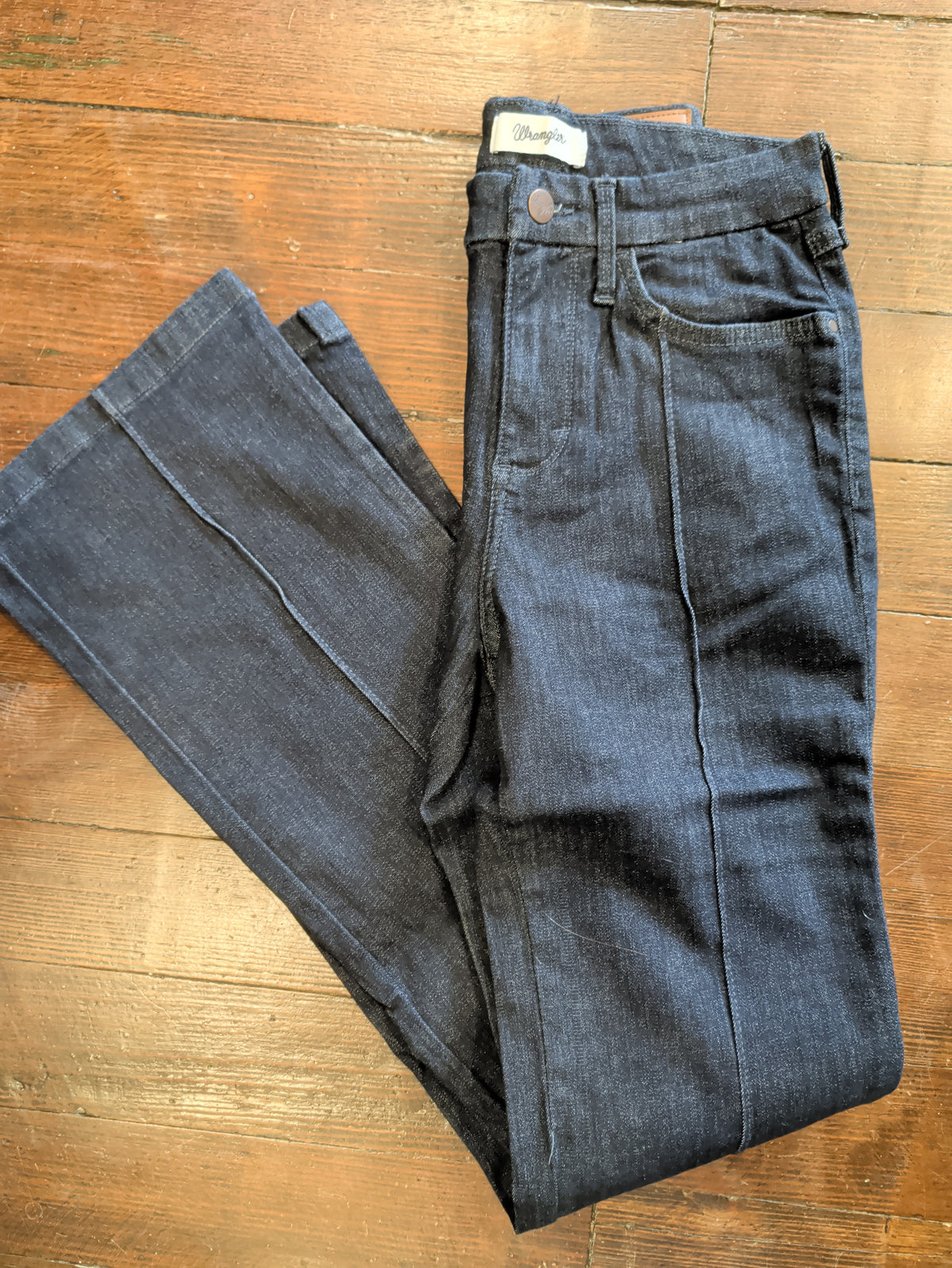 Folded front view of Wrangler Bespoke Camryn jeans showing dark denim, front pockets and vertical pintucks.