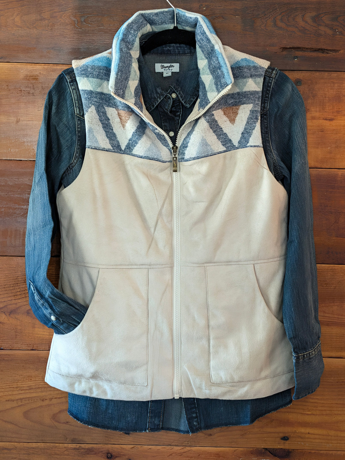 Cream zip-front vest with geometric yoke and patch pockets, layered over a denim shirt.