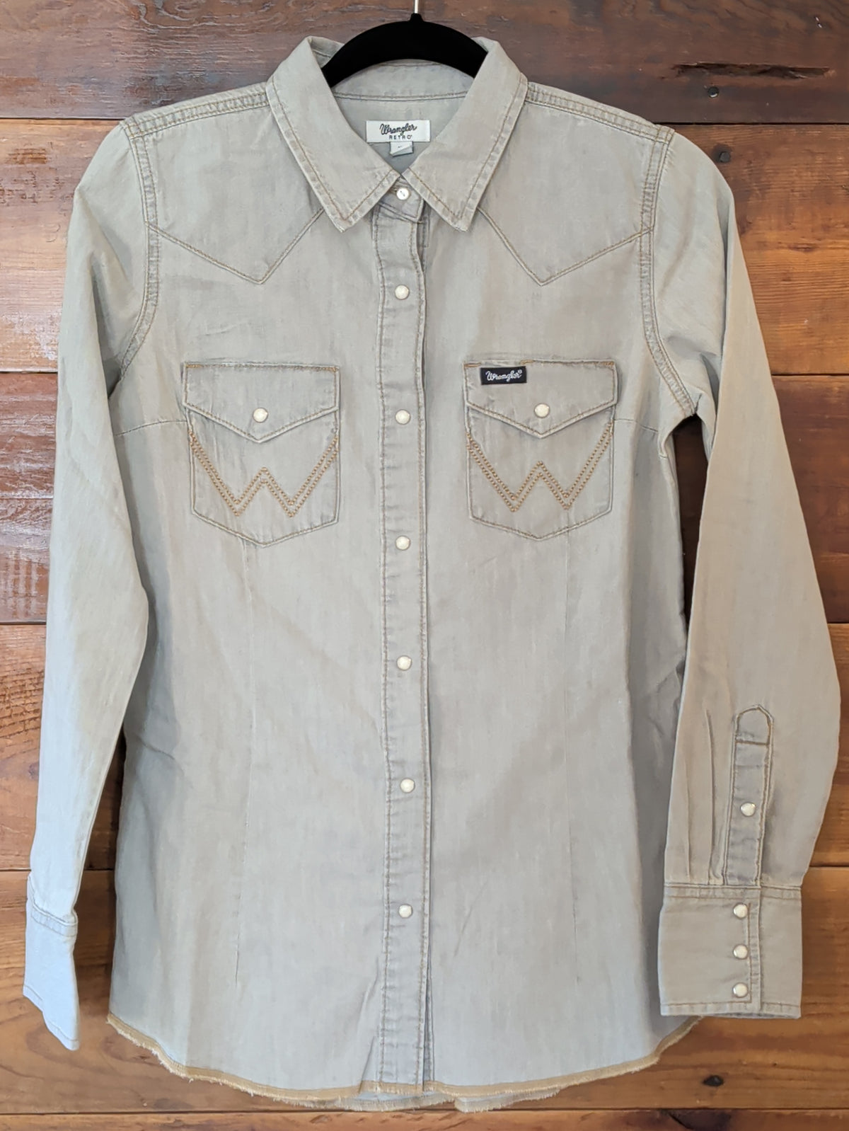Wrangler women’s grey denim Western snap shirt with long sleeves, pointed yokes and W-embroidered flap chest pockets.