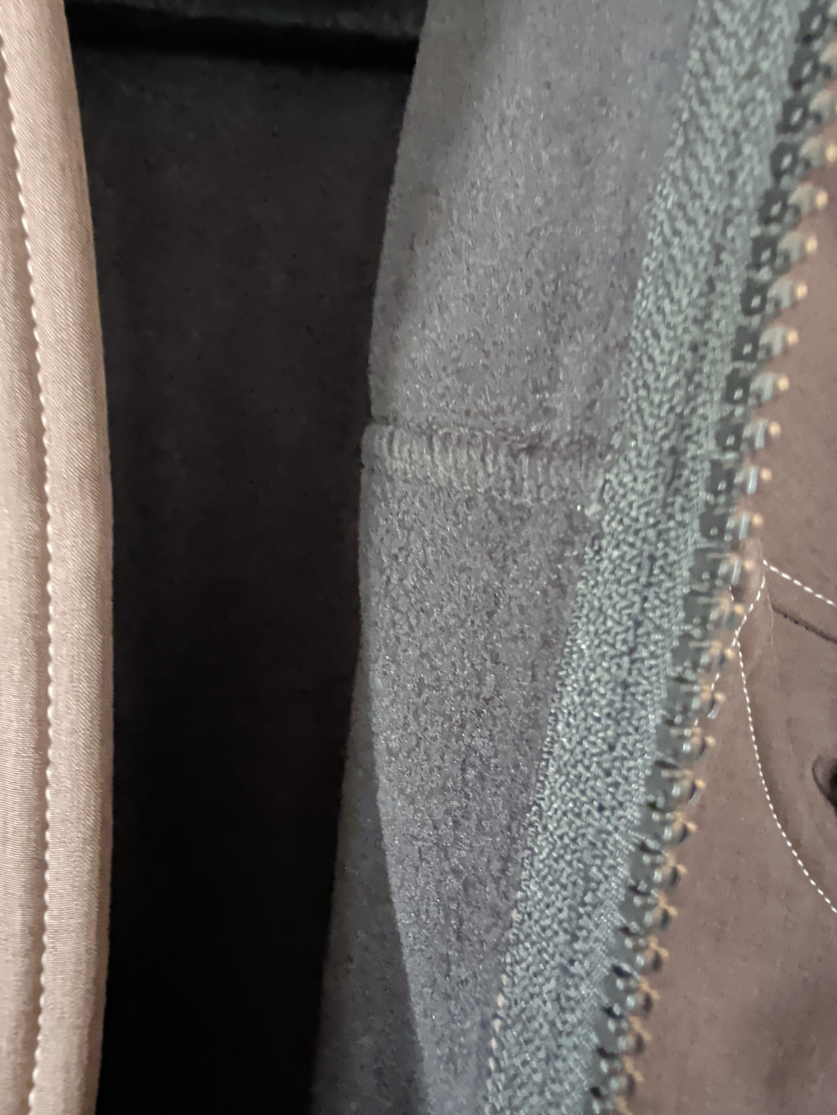 Close-up of the jacket’s dark textured interior beside the front zipper