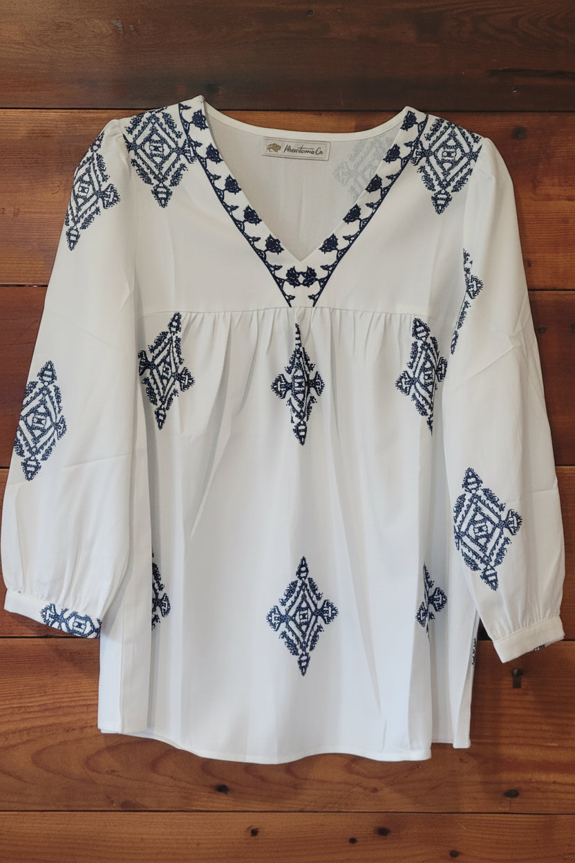 White blouse with blue embroidery on a wooden surface