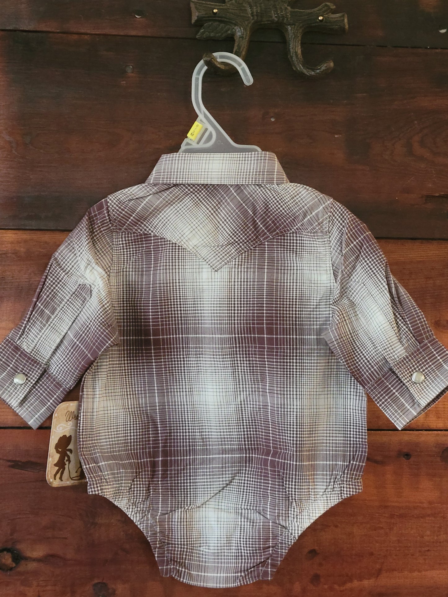 Plaid shirt on a hanger against a wooden background