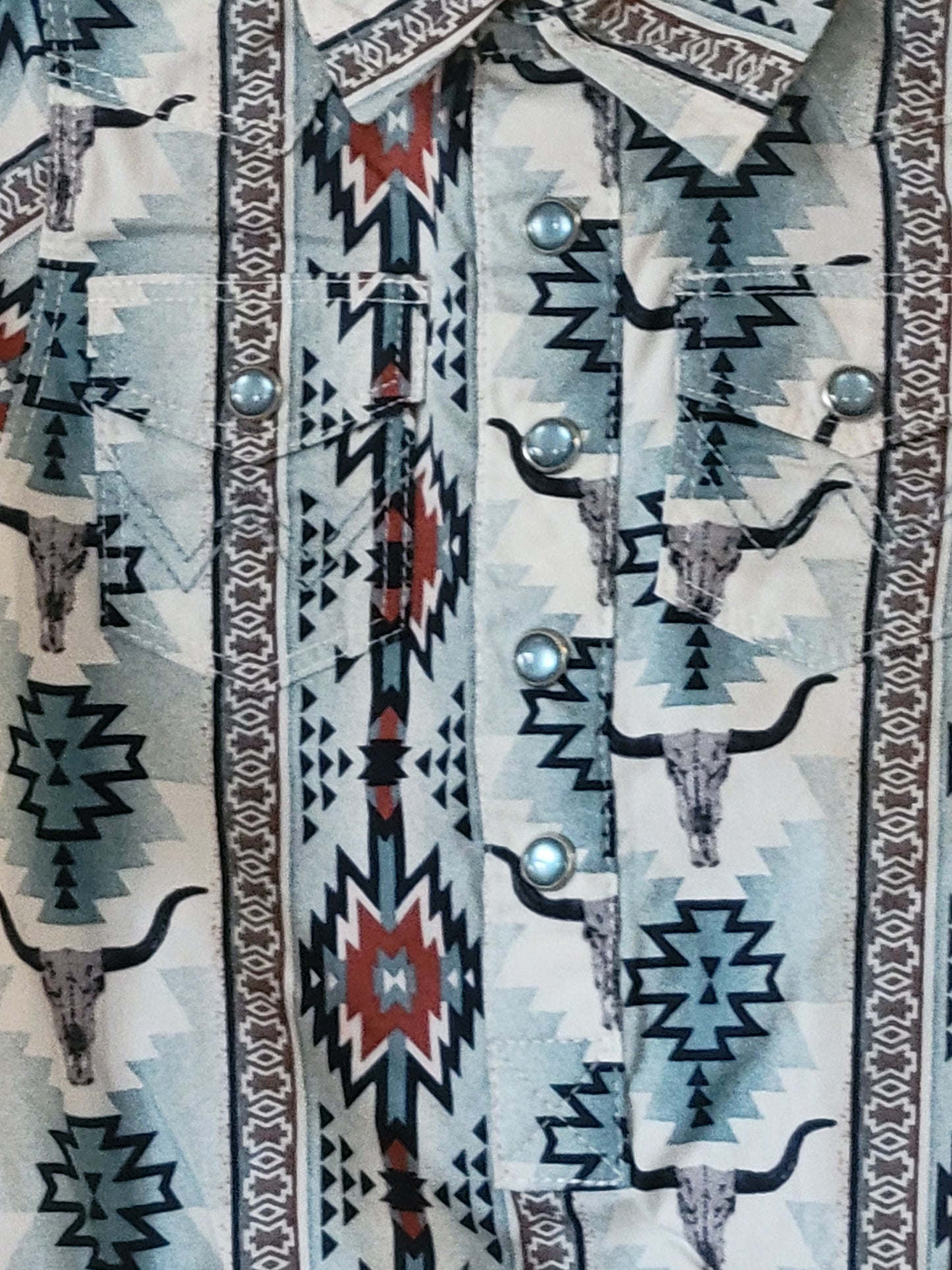 Close-up of a patterned fabric with geometric designs in black, red, and white on a light blue background.