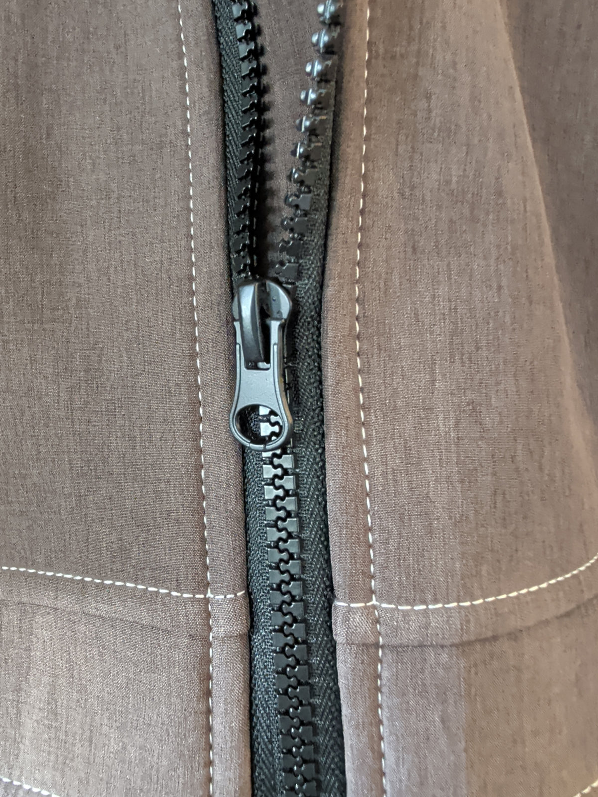 Close-up of the brown softshell jacket’s black front zipper and light contrast stitching