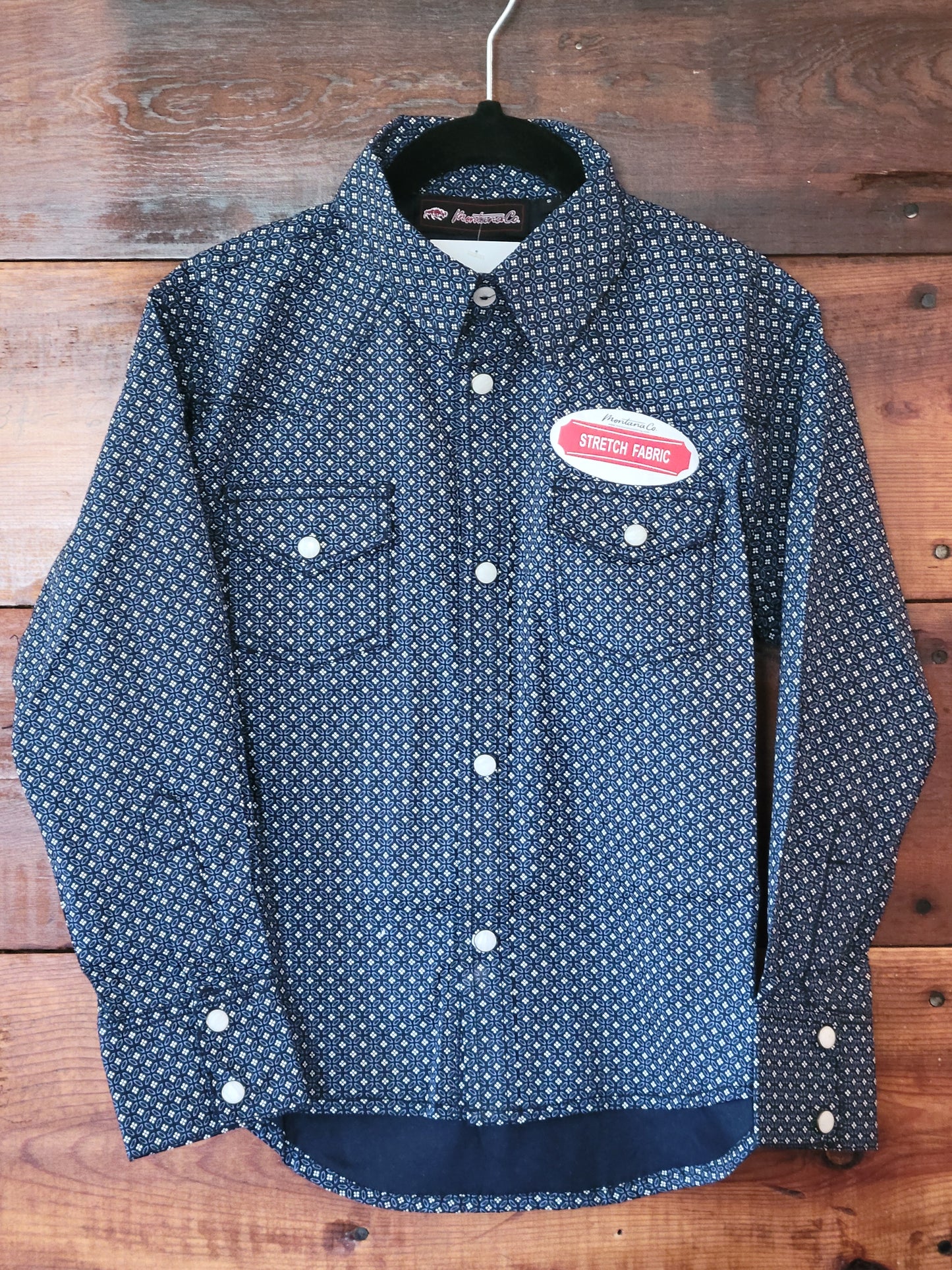 Blue patterned shirt with a red label on a wooden background