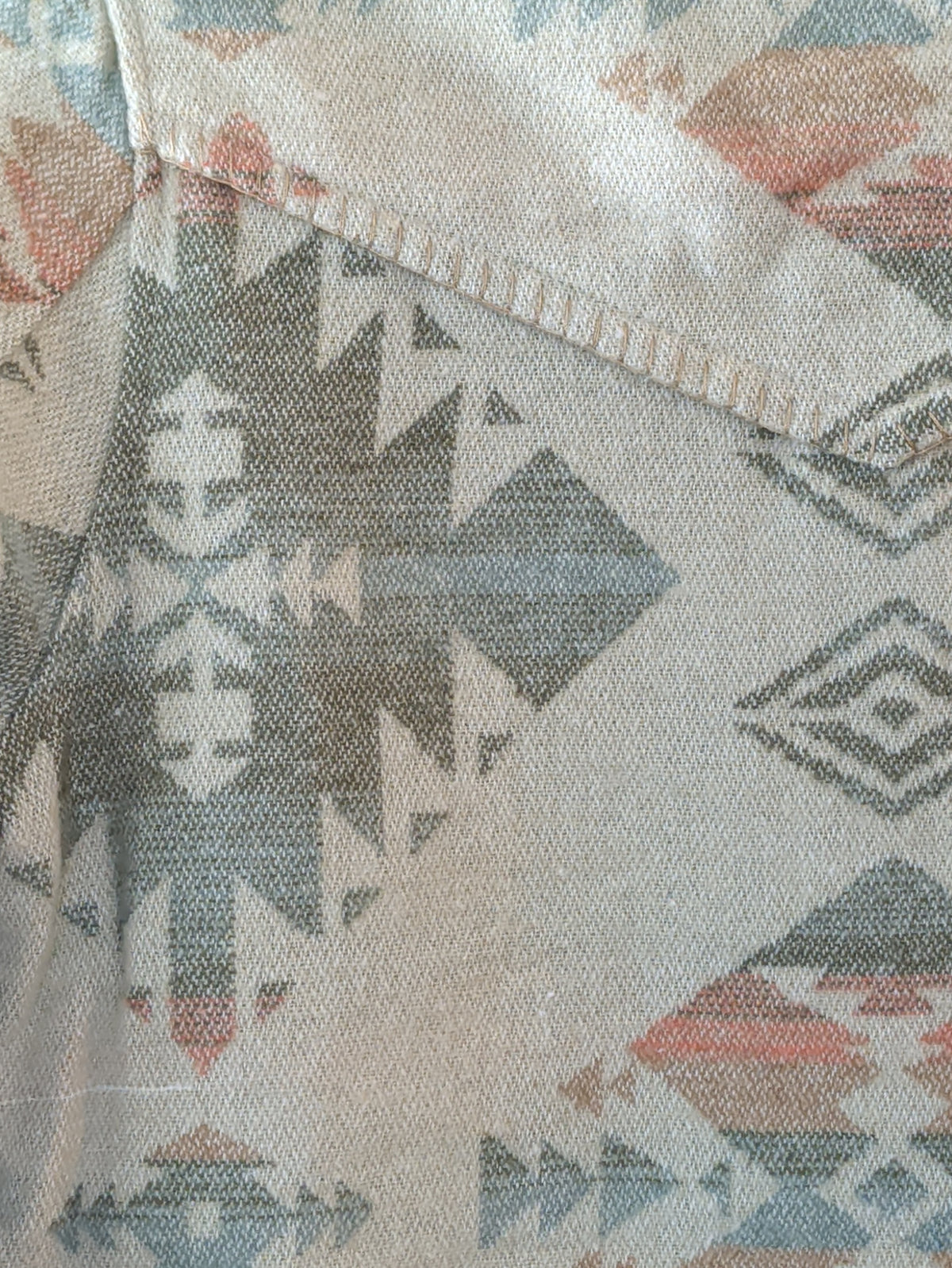 Close-up of blanket stitching along the pointed back yoke with sage, blue, and peach Southwestern motifs

