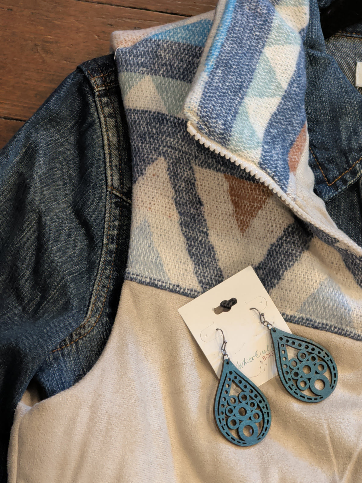 Close-up of cream vest’s geometric yoke, styled with turquoise teardrop earrings.