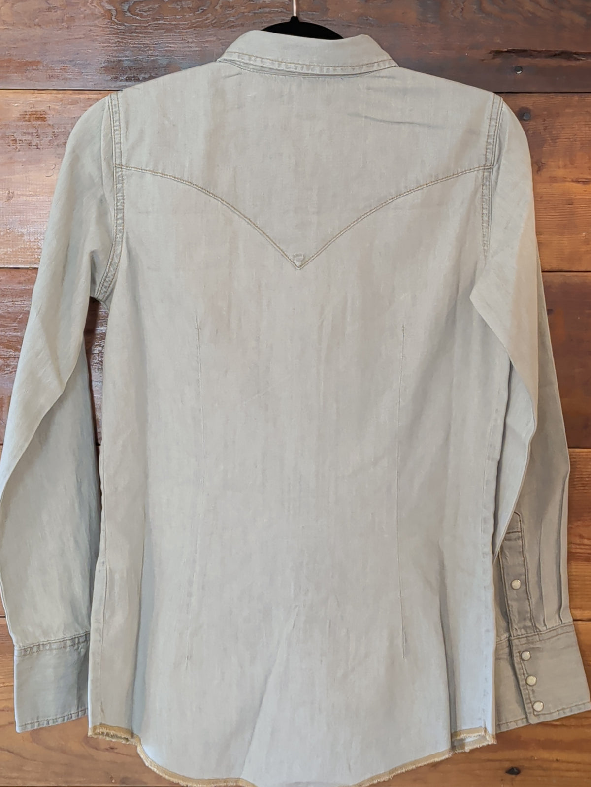 Back of the Wrangler women’s grey denim shirt showing the pointed Western yoke, long sleeves and curved hem.