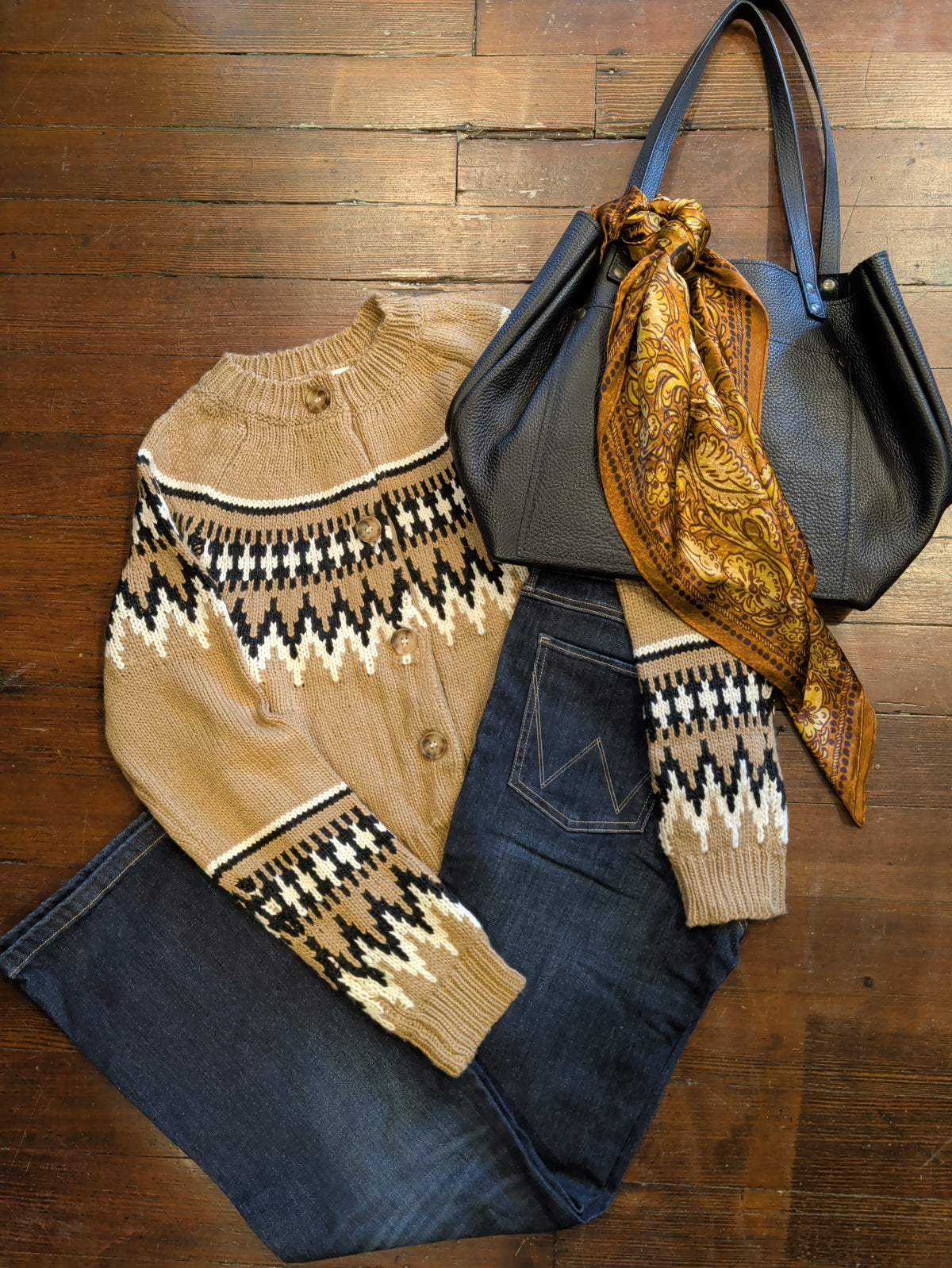 Light brown Fair Isle cardigan styled with dark jeans, a black tote, and a gold patterned scarf.