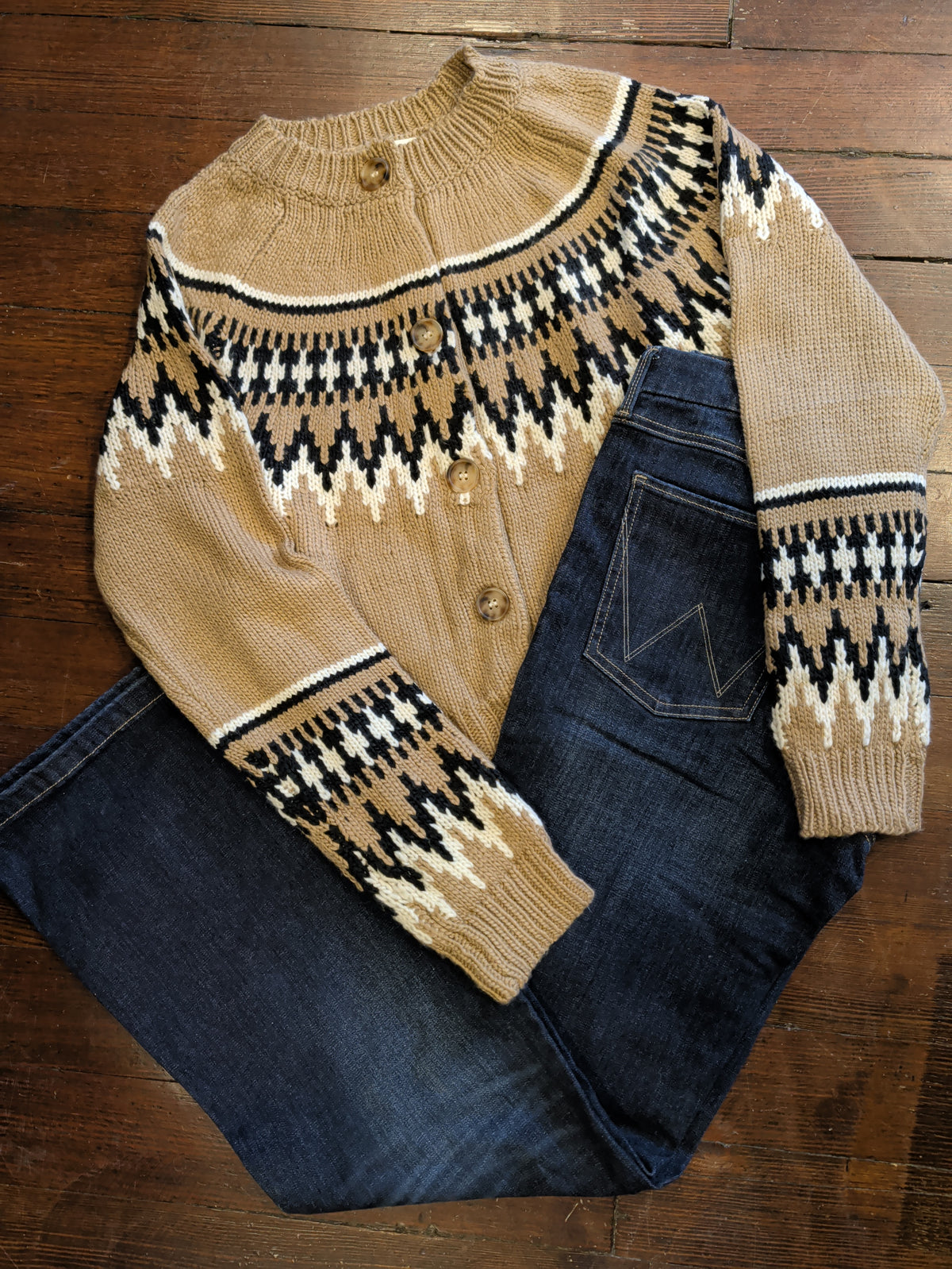 Light brown button-front Fair Isle cardigan with black and cream patterning, styled with dark jeans.