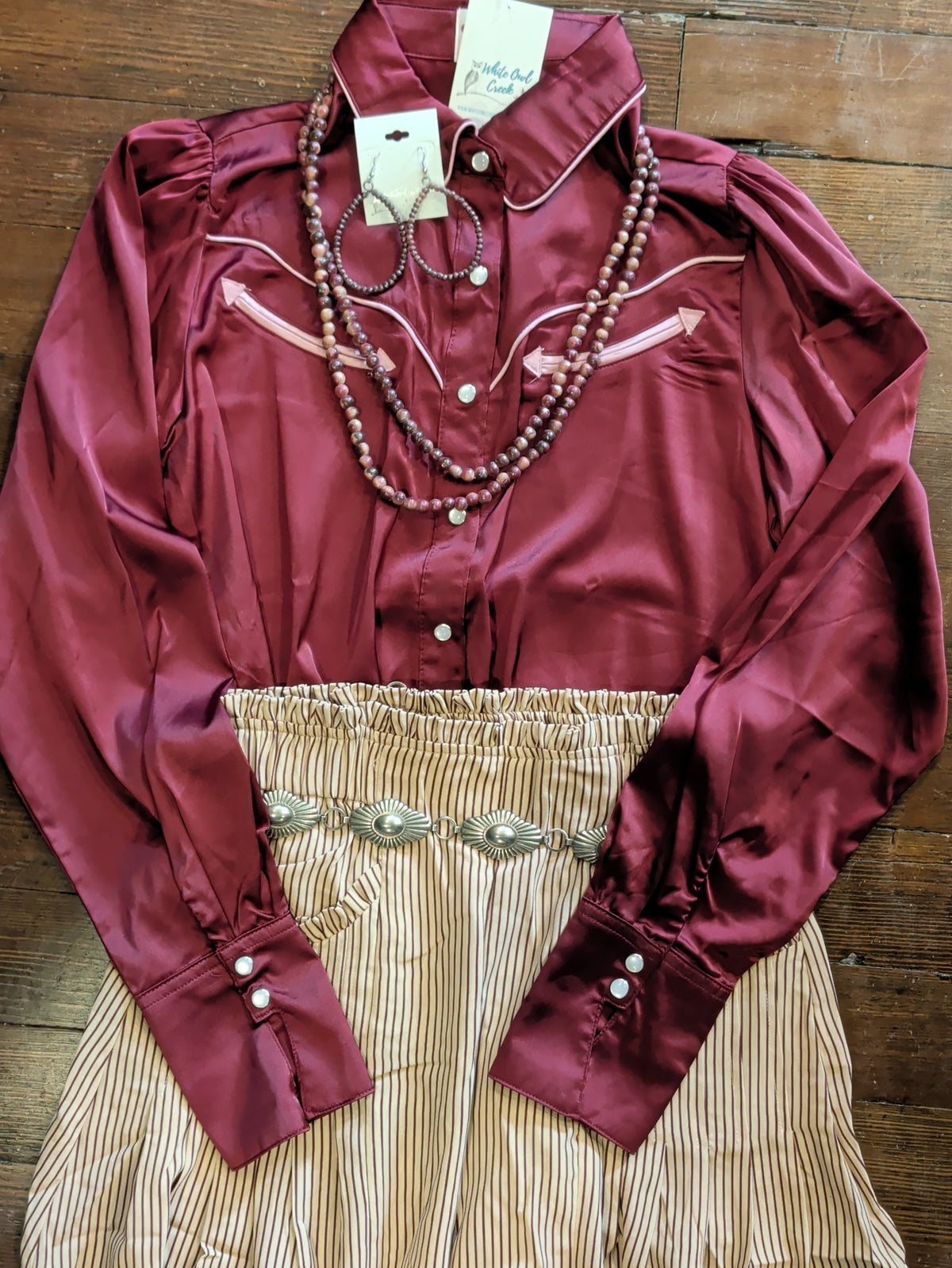 Tan palazzo pants with burgundy pinstripes styled with a burgundy Western blouse, silver-tone concho belt, and beaded jewelry.