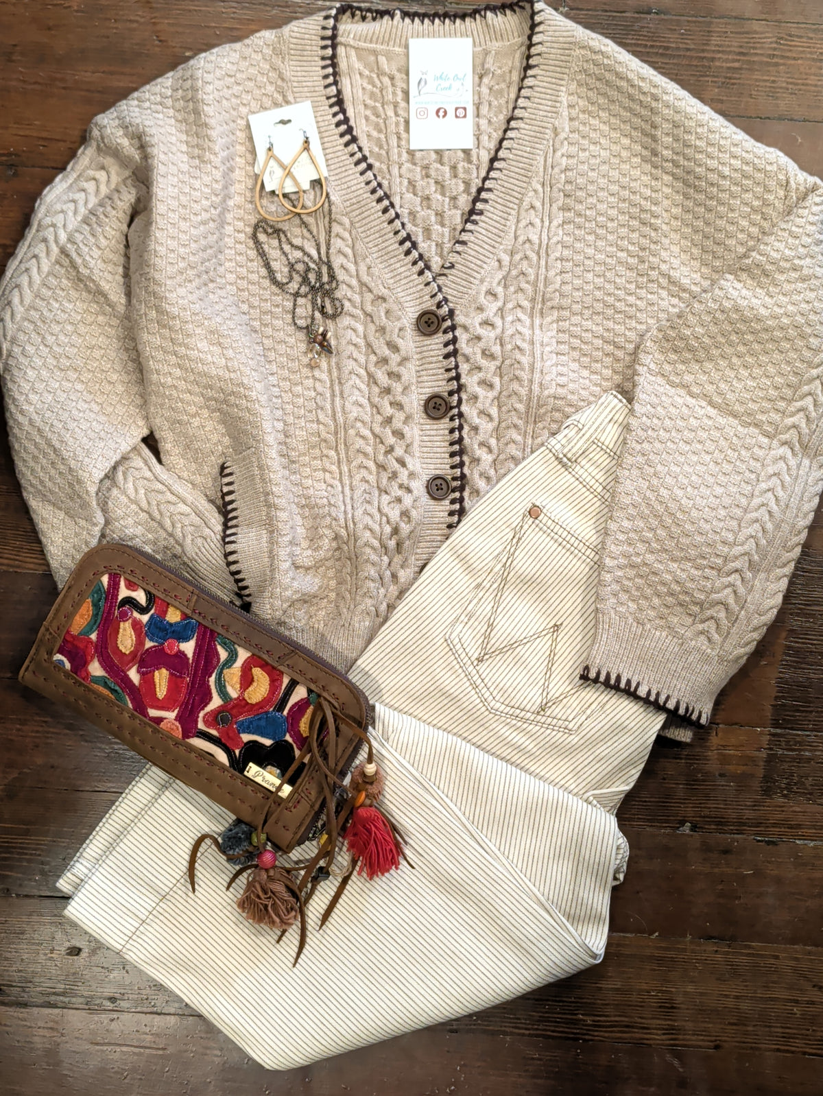  Mocha Blanket Stitch Cardigan with cream pinstriped pants, jewelry and a colorful clutch in an outfit flat lay.