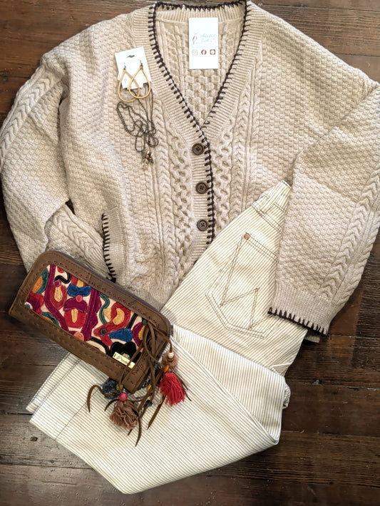  Mocha Blanket Stitch Cardigan with cream pinstriped pants, jewelry and a colorful clutch in an outfit flat lay.