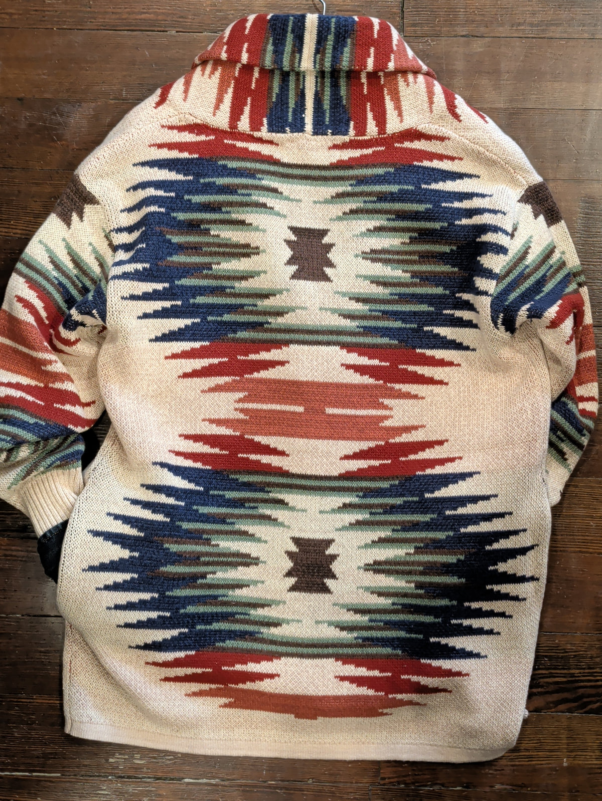 Back view of cream Southwestern-pattern cardigan with a shawl collar and rust, navy, sage, and brown geometric motifs.