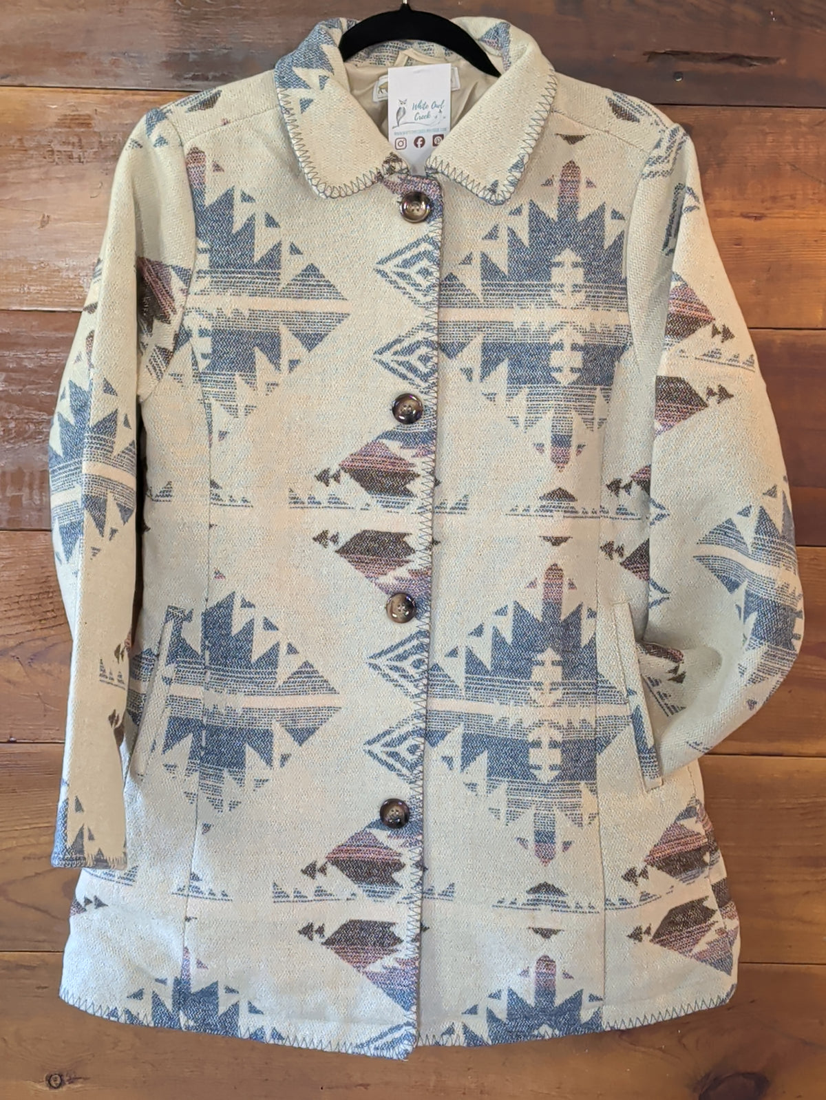 Cream Southwestern print coat with muted blue and mauve geometric motifs, button-front closure, and blanket stitching