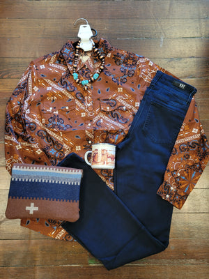 Brown Bandana western snap shirt paired with dark denim jeans a vintage cowgirl candle and fun copper and turquoise necklace